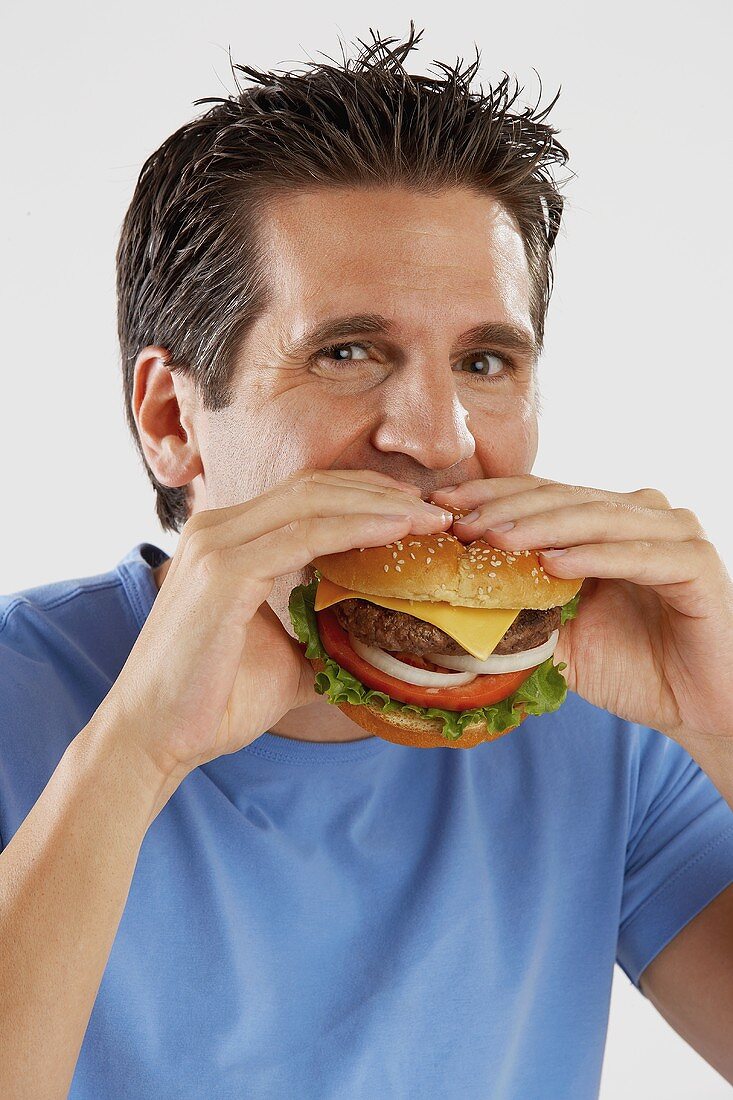 Mann beisst in saftigen Cheeseburger