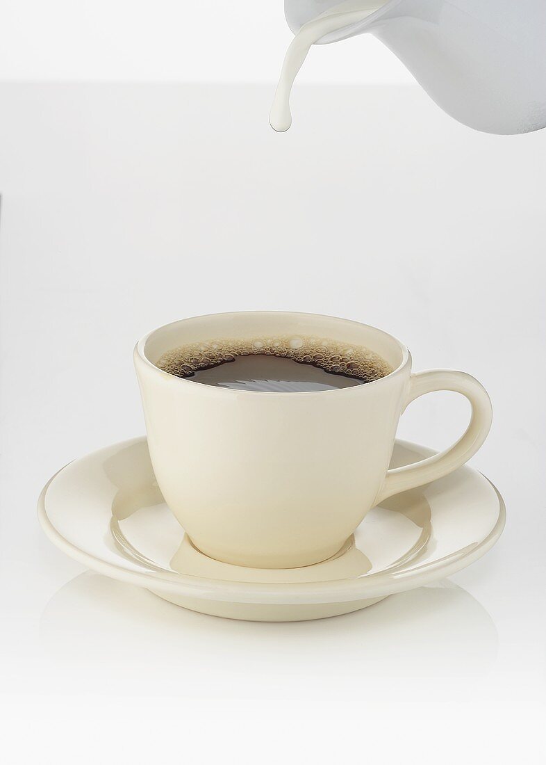 Milch in Kaffeetasse gießen