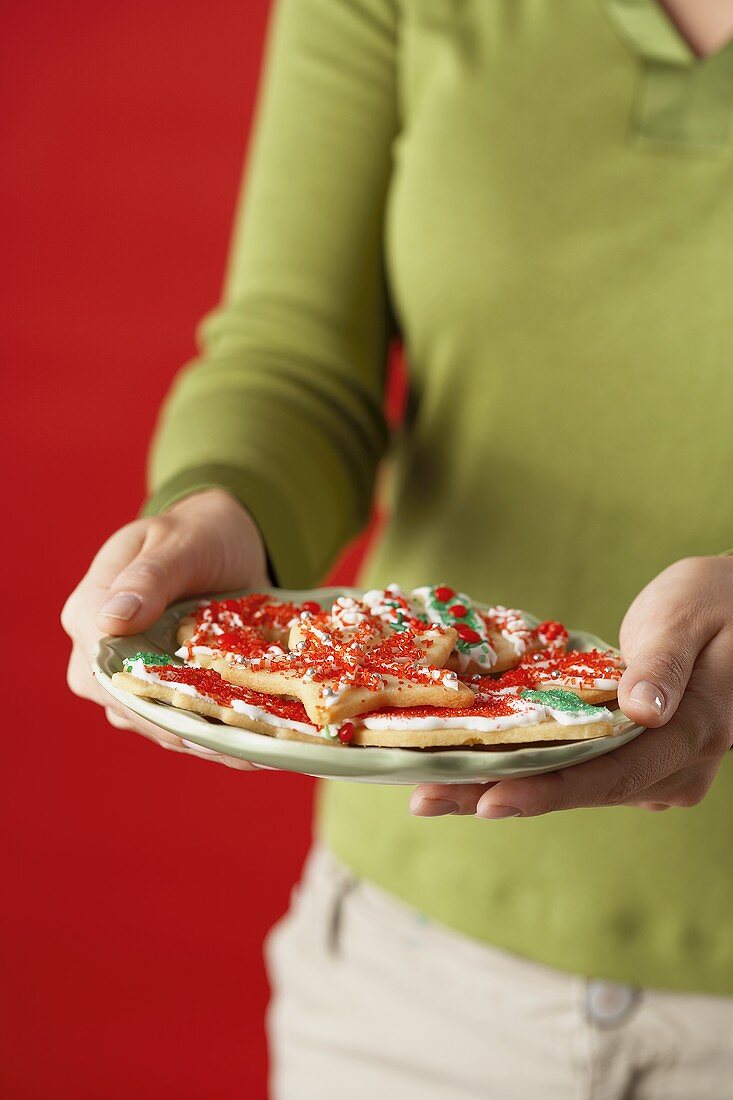 Frau hält Teller mit bunten Weihnachtsplätzchen