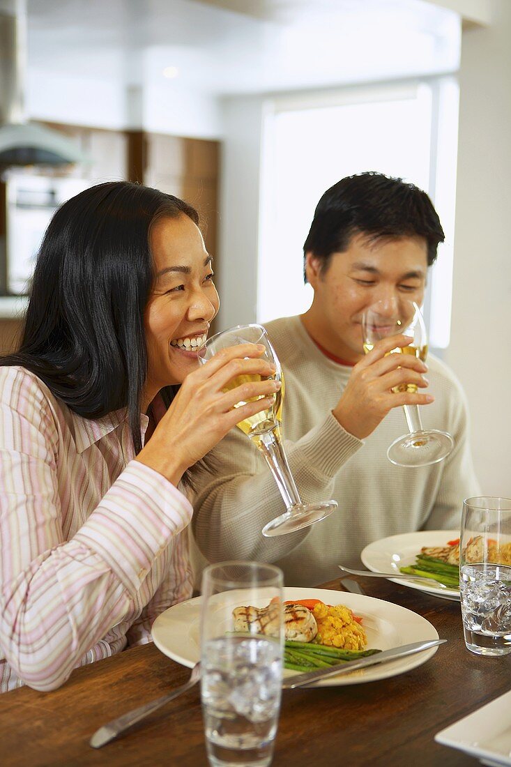 Junges Paar trinkt Weißwein beim Mittagessen in der Küche