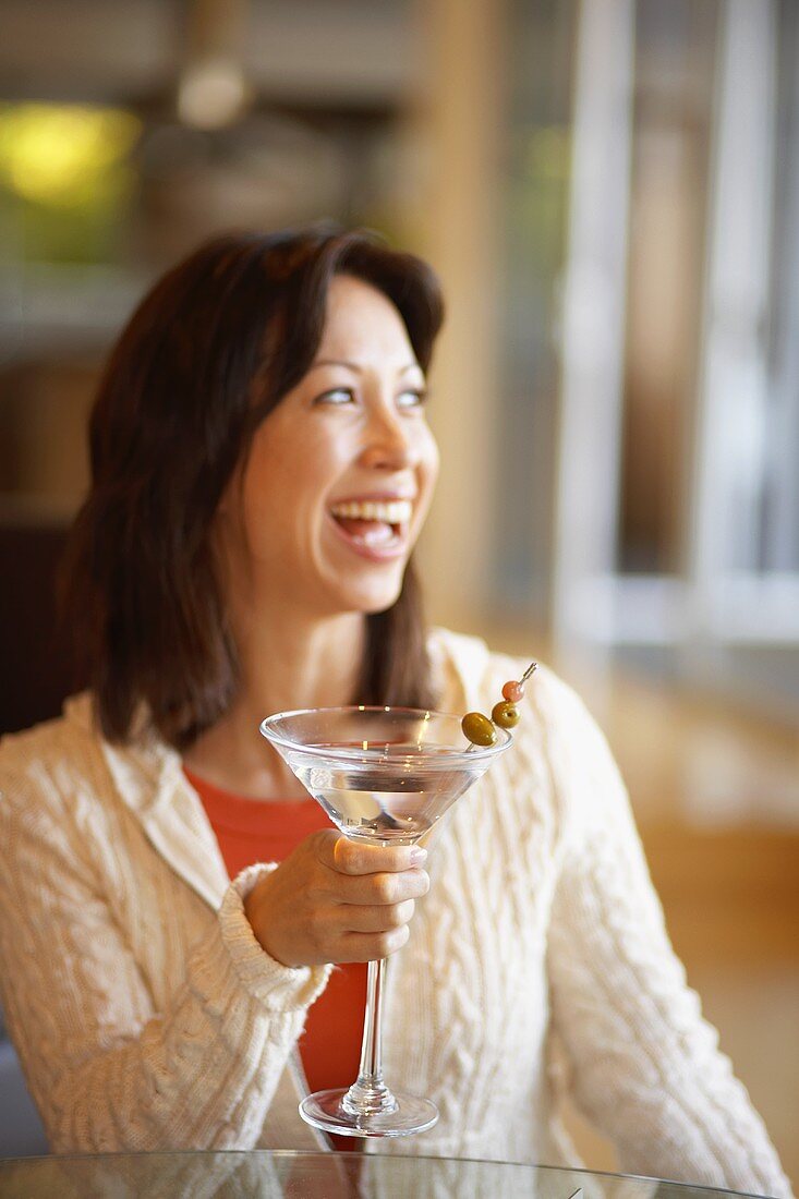 Lachende Frau hält Martiniglas