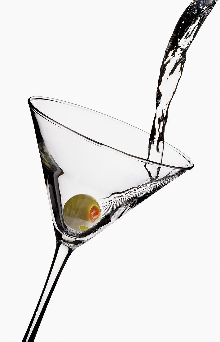 Martini in Glas mit Olive einschenken