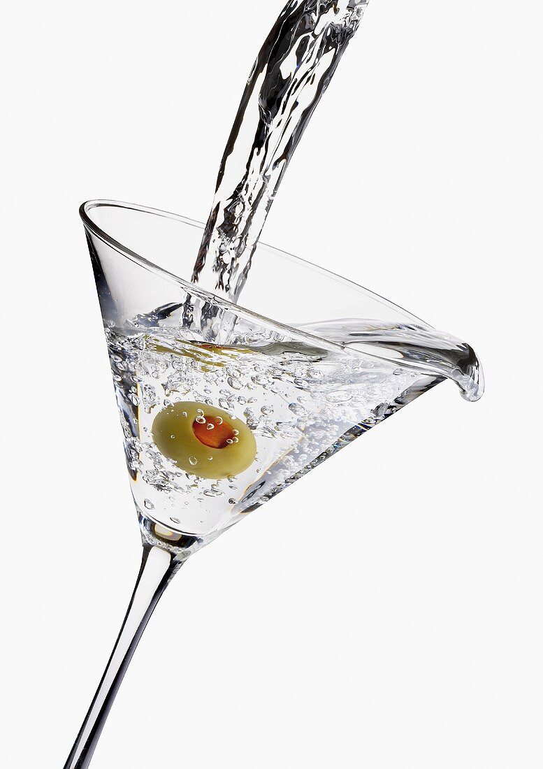 Martini in Glas mit Olive einschenken