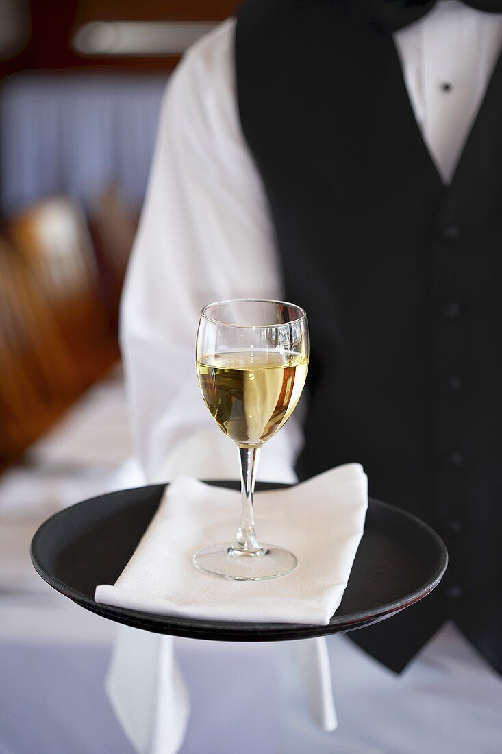Kellner serviert Glas Weißwein