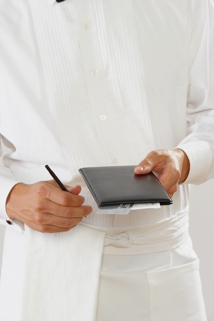 A Waiter Holding a Leather Bi-fold and Pen