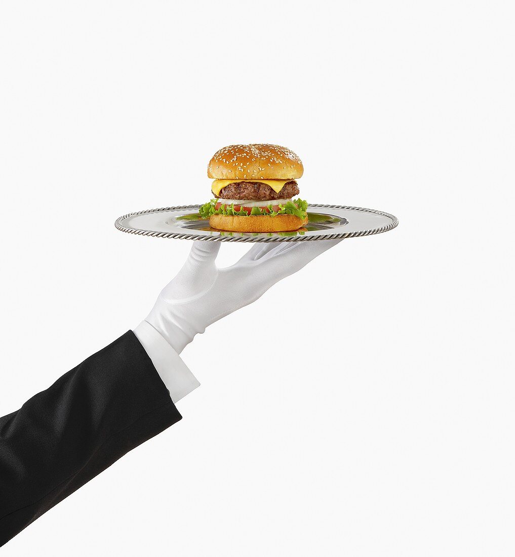 Hand mit weißem Handschuh hält Tablett mit Cheeseburger