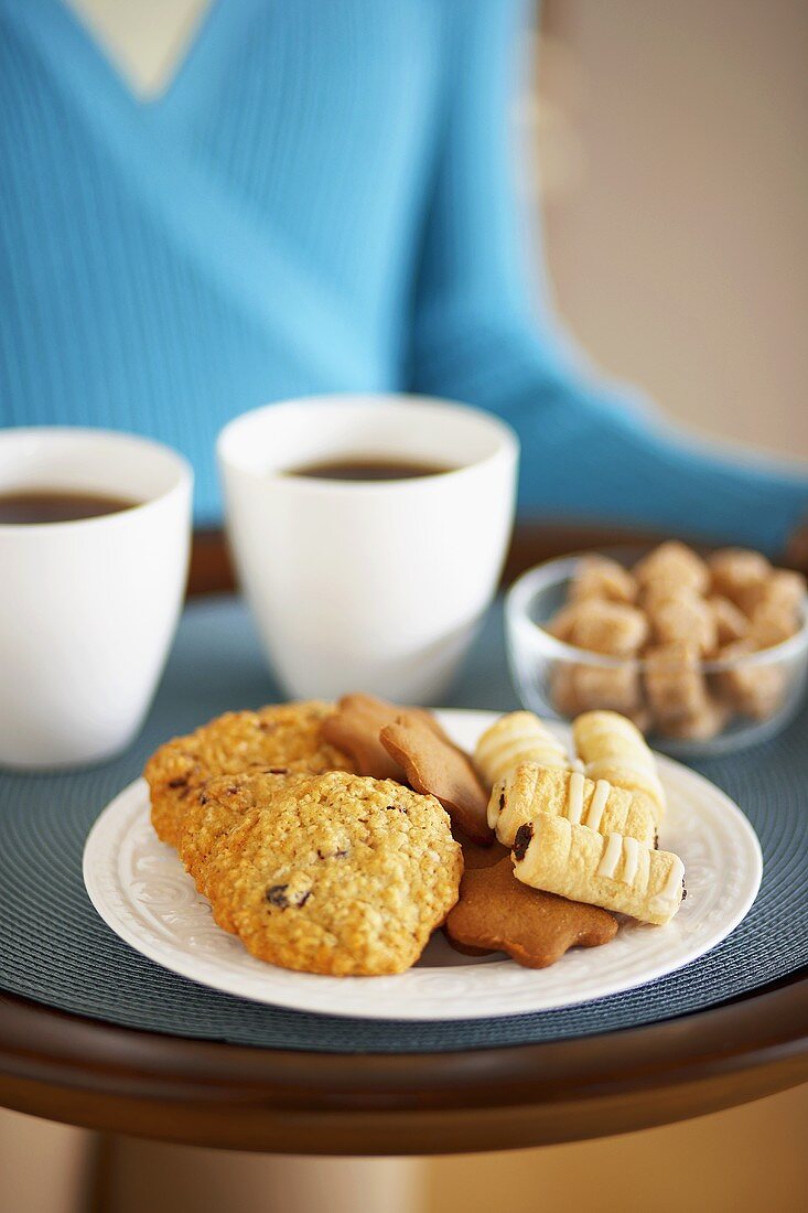 Frau trägt Tablett mit Plätzchen und Kaffee