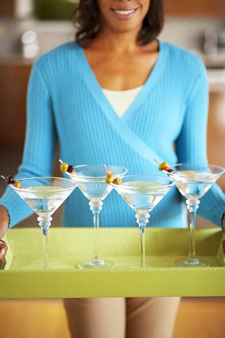 Frau trägt Tablett mit vier Martinis