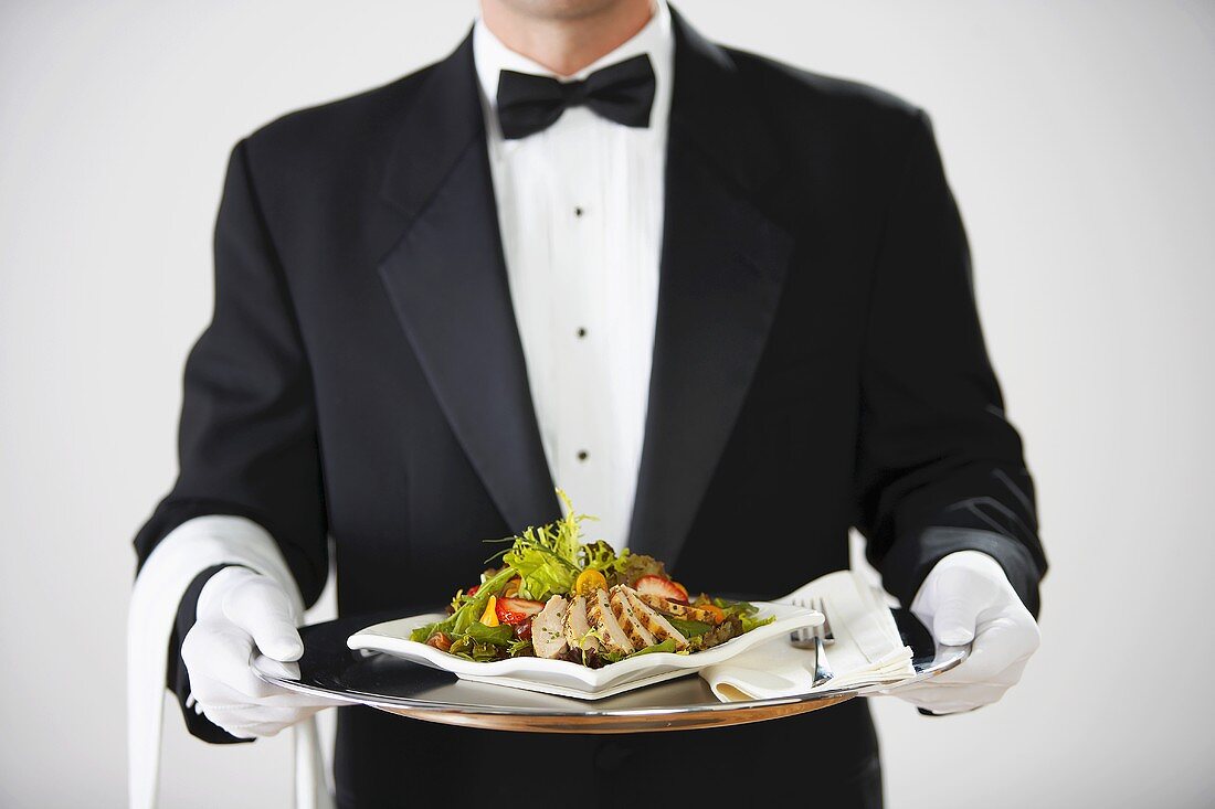 Butler serviert Hähnchensalat auf Silbertablett