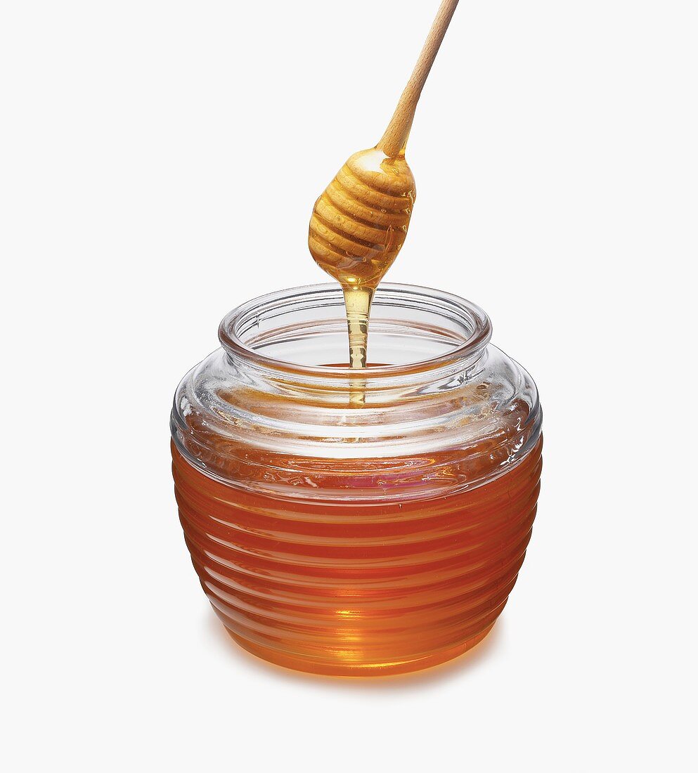 Honig tropft von Honigkamm in Glas