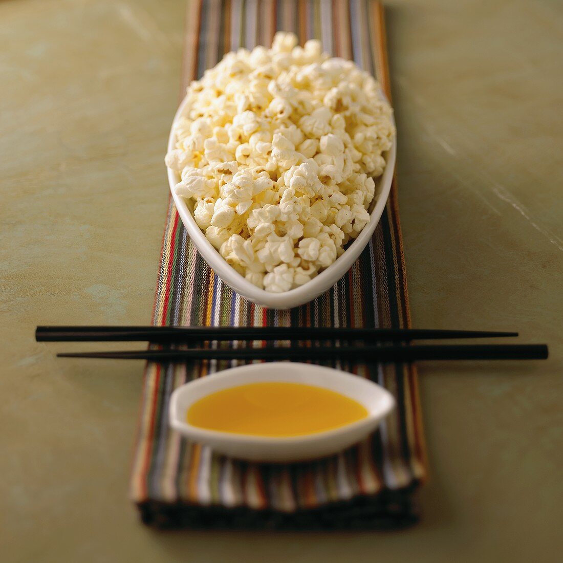 A Bowl of Popcorn with Melted Butter and Chopsticks