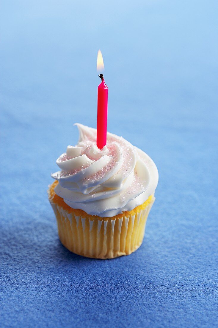 A Yellow Cupcake with Vanilla Frosting and a Lit Red Candle