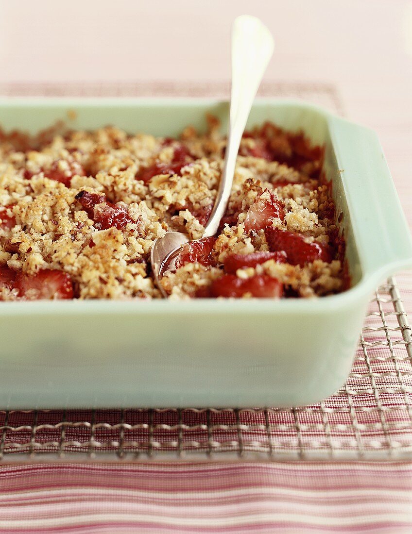 Strawberry Crisp in a Green Baking Dish with a Spoon