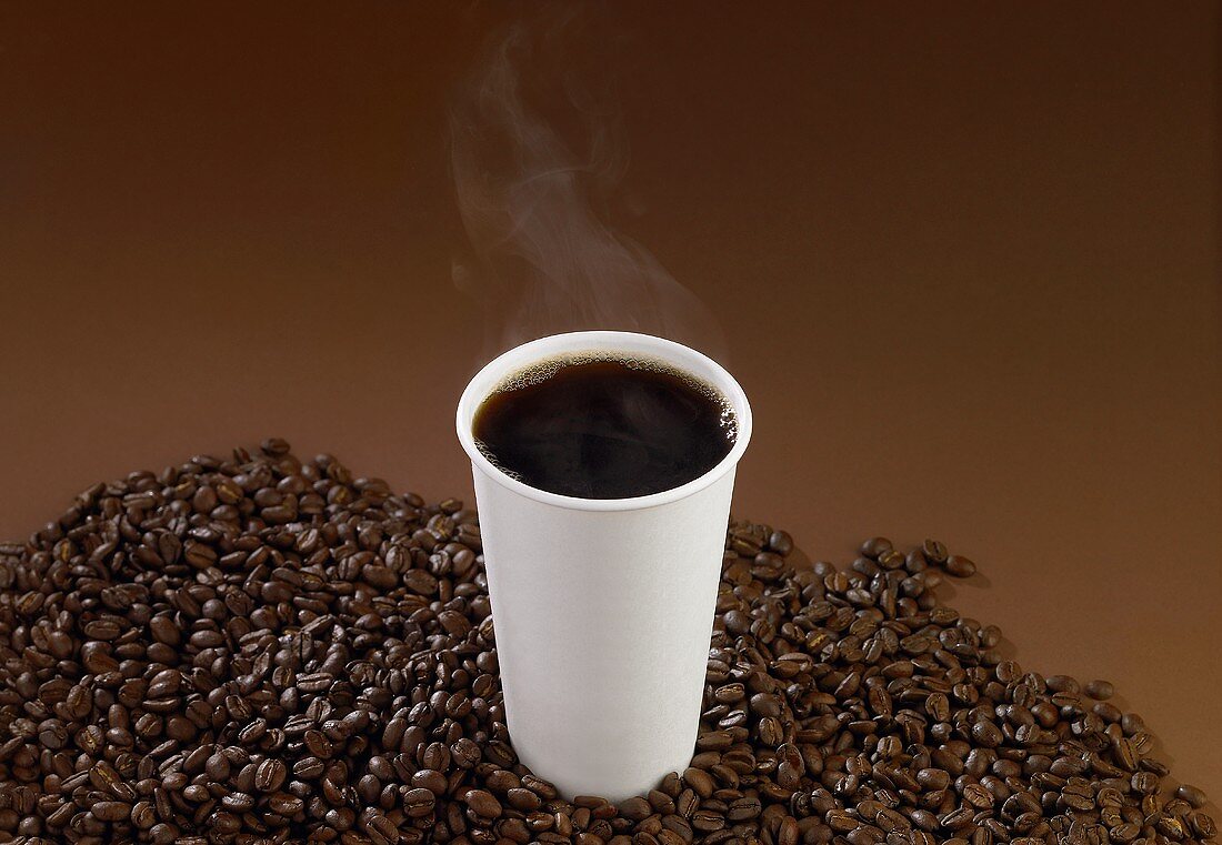 A Steaming Cup of Black Coffee on a Pile of Coffee Beans