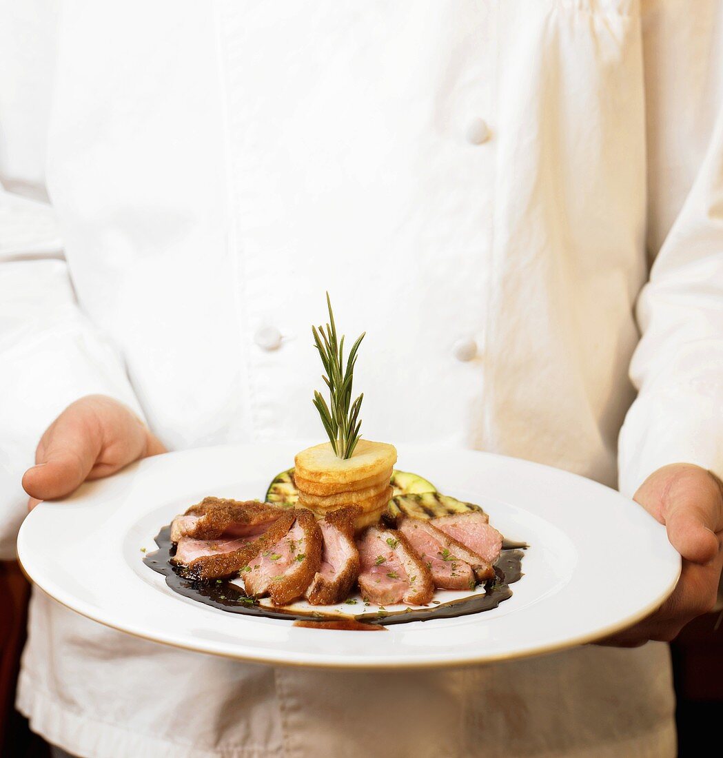 A Chef Holding Sliced Duck Breast Entrée