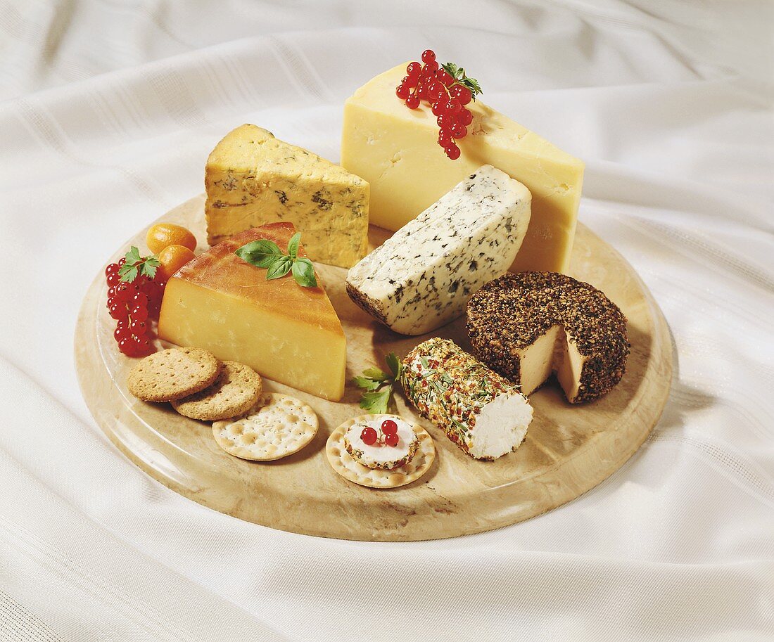 Cheese and crackers on a wooden board with red currants