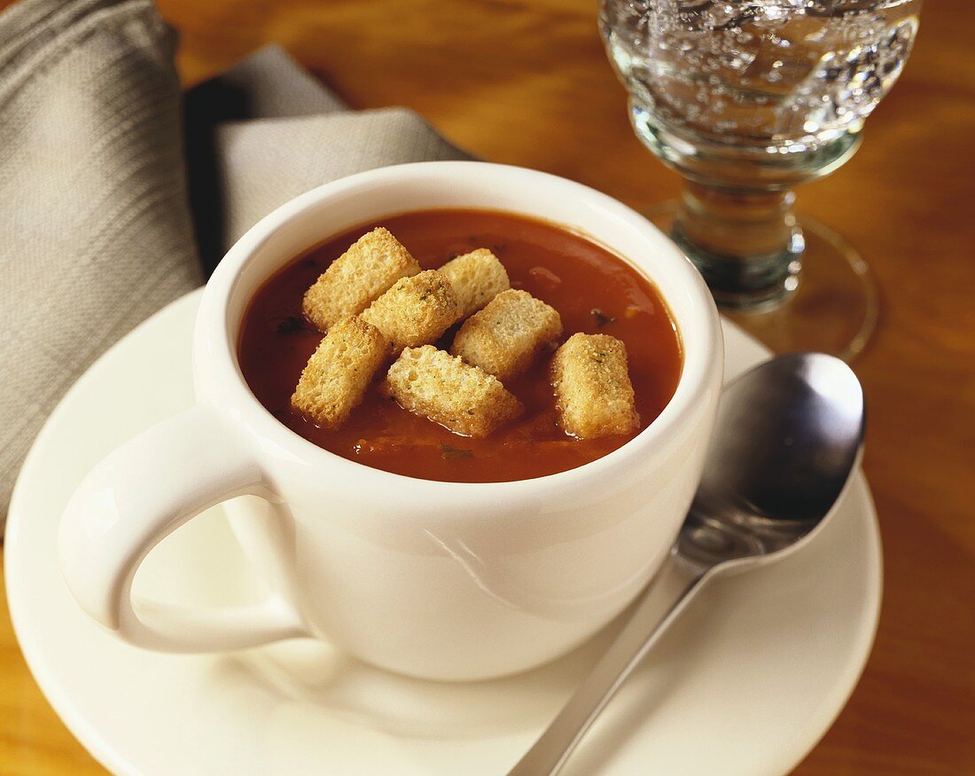 A cup of tomato basil soup with croutons
