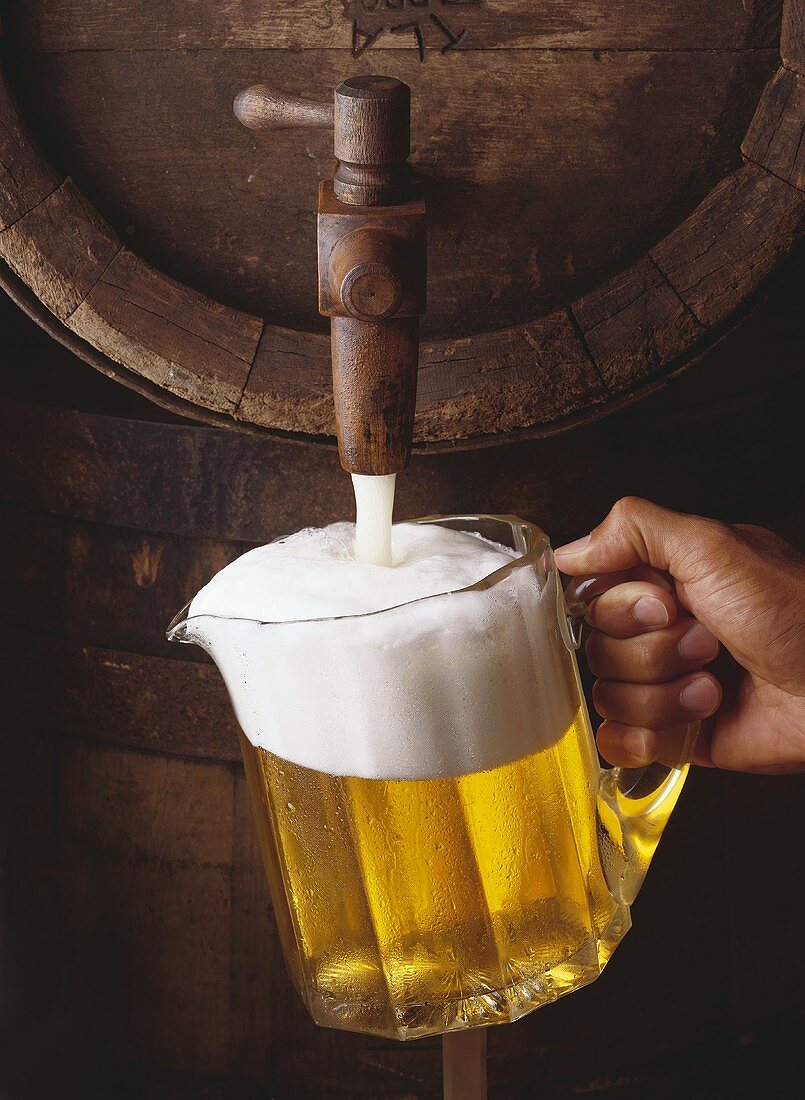 Pouring a pitcher of beer from a wooden keg