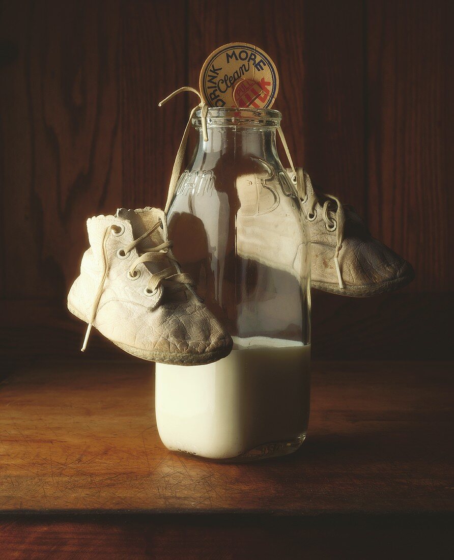 Eine Flasche Milch mit Babyschuhen