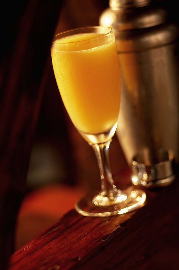 Glass of Whiskey Sour with Orange Juice on Bar; Cocktail Shaker