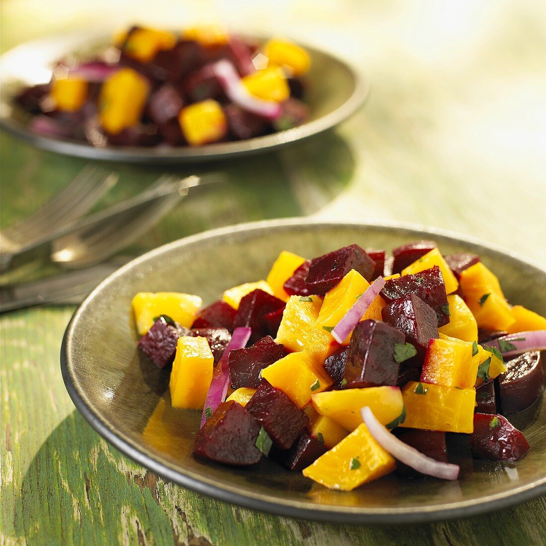 Red and Golden Beet Salad with Red Onion Served on Green Plates
