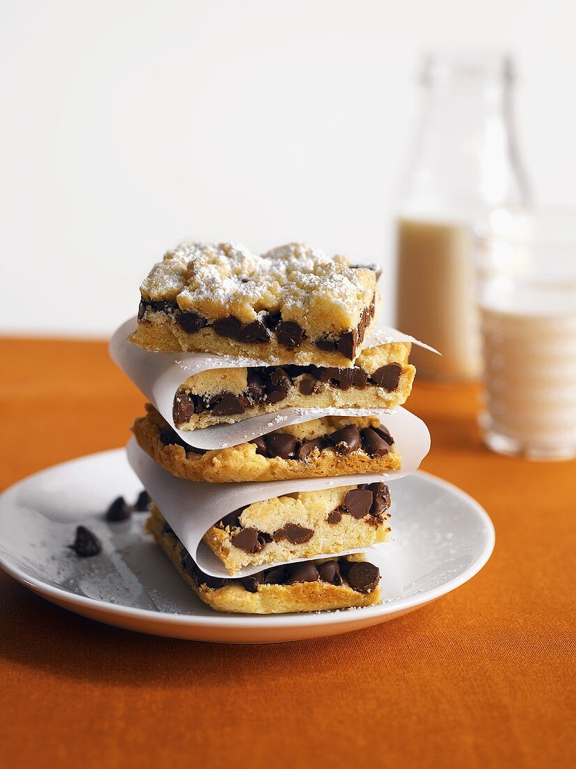 A Stack of Chocolate Chip Cookie Bars with Powdered Sugar and Milk