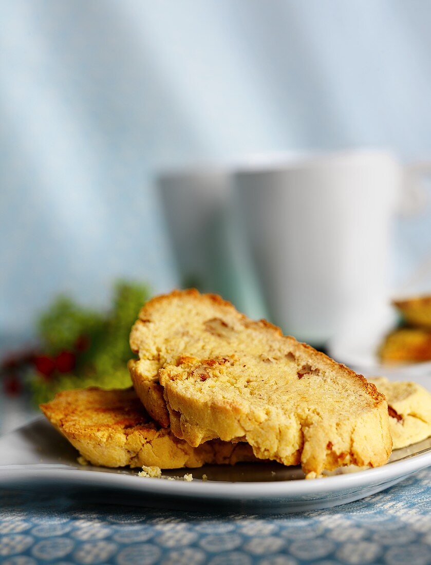 Biscotti auf Teller, im Hintergrund Kaffeetassen