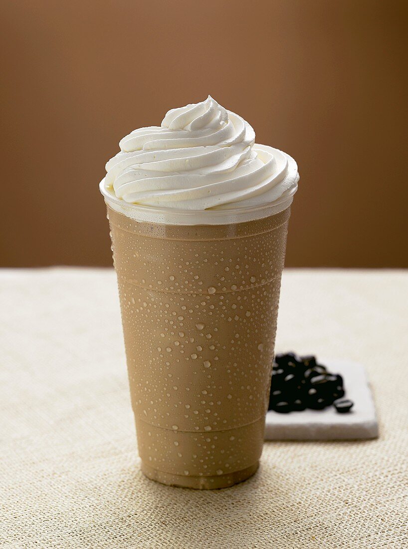 Iced Coffee Served in Tall Glass with Whipped Cream; Coffee Beans