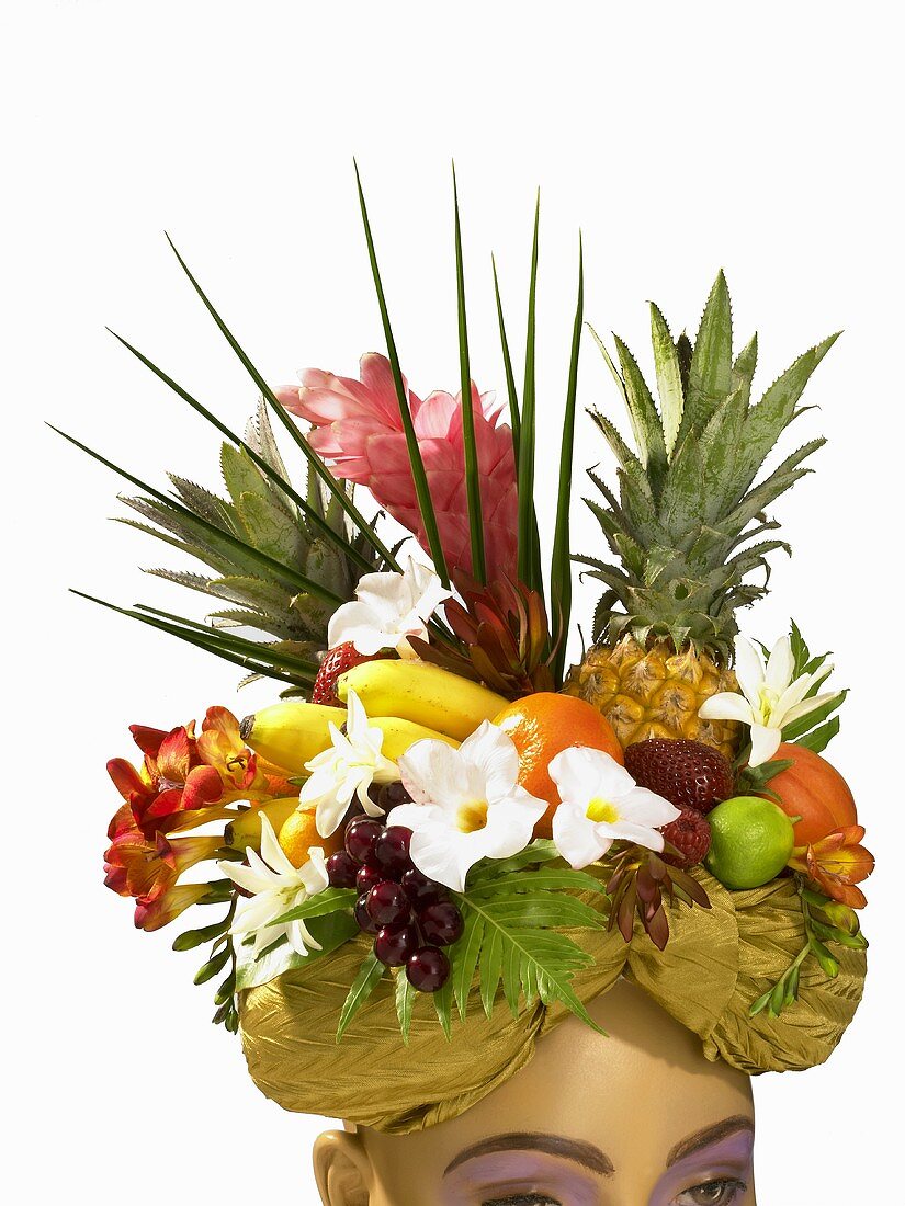 Frauenkopf trägt Hut aus Früchten und Blumen