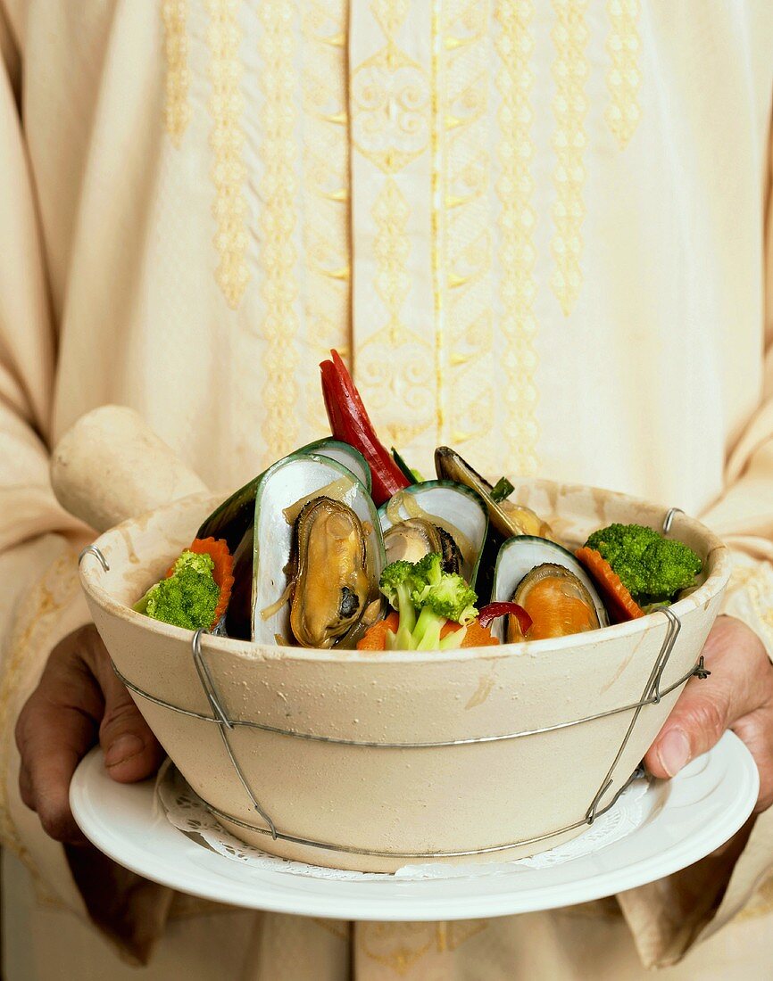 Waiter Holding Pot of Steamed Mussels with Mixed Steamed Vegetables