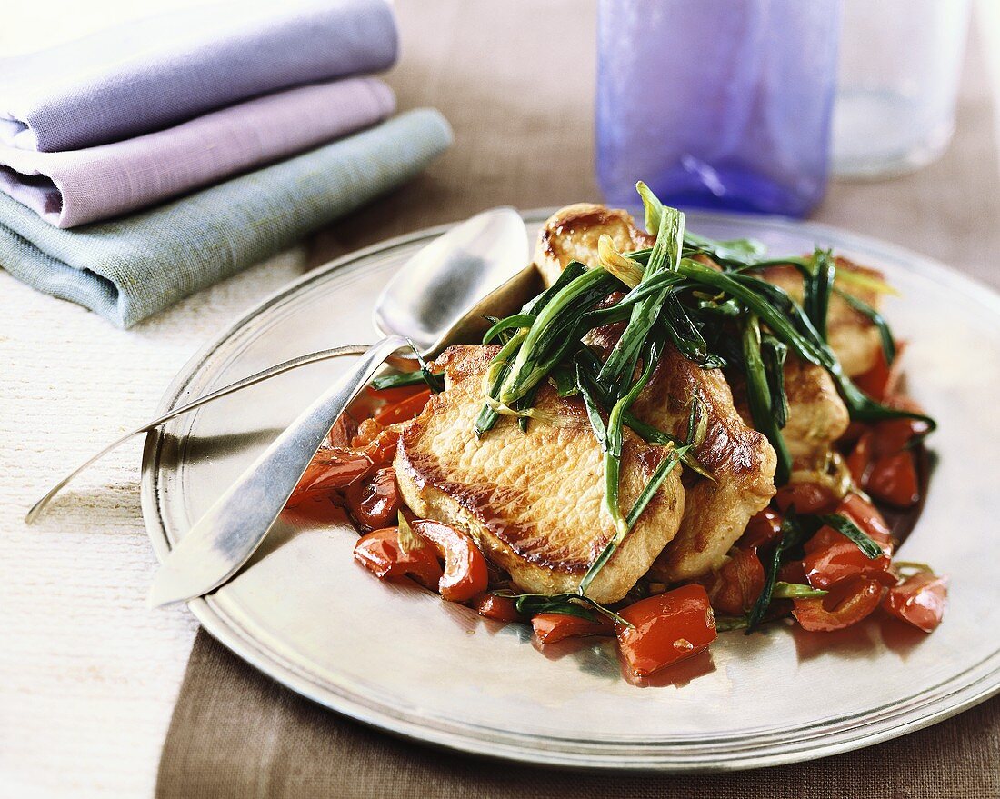 Platter of Roasted Pork Chops Topped with Roasted Green Onions on Bed of Roasted Red Peppers