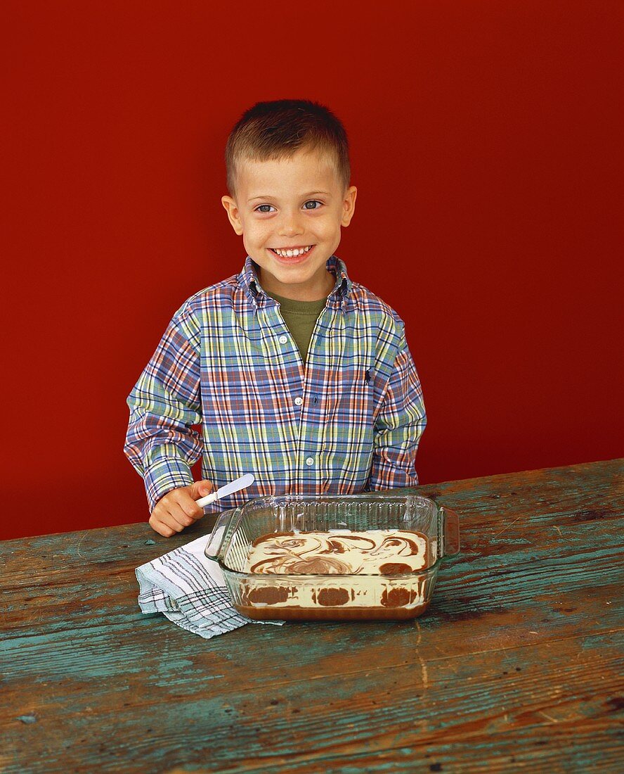 Junge verziert Cheesecake-Brownies mit Buttermesser