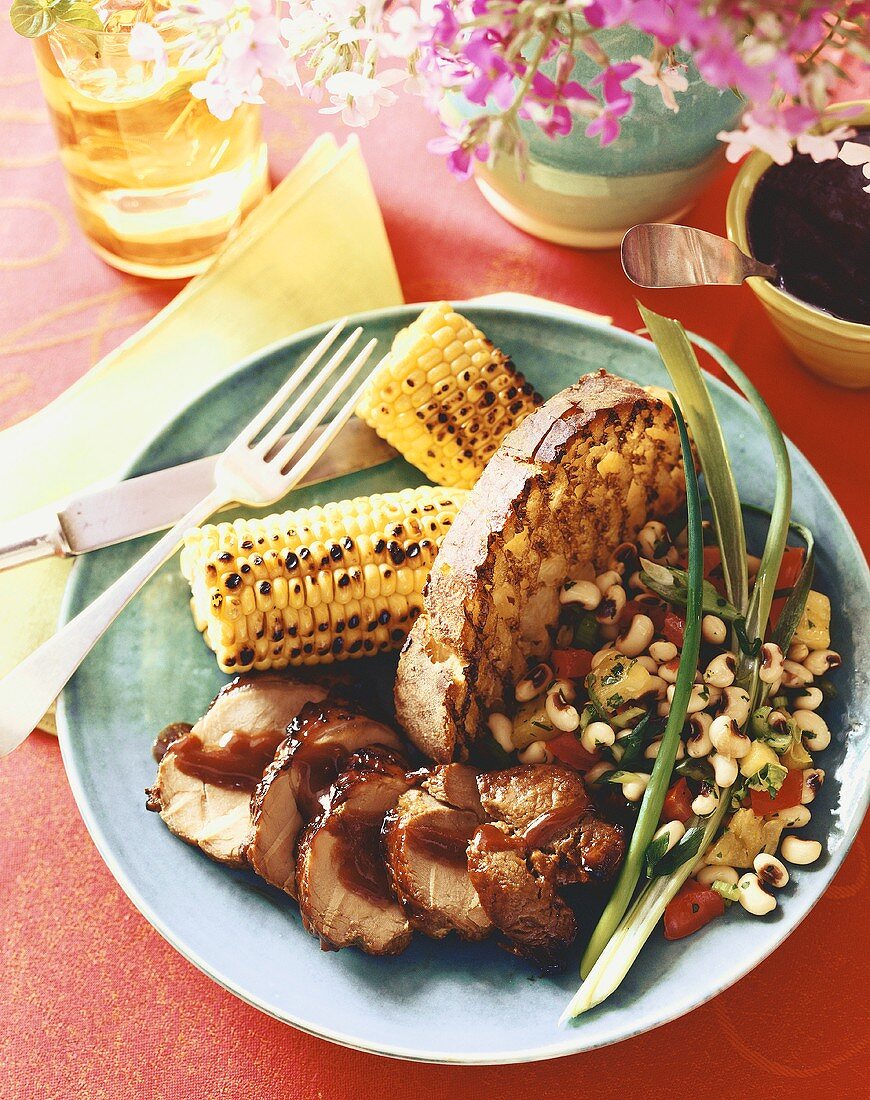 Serving of Sliced Pork with Barbecue Sauce, Grilled Corn on the Cob, Grilled Bread and Bean Salad