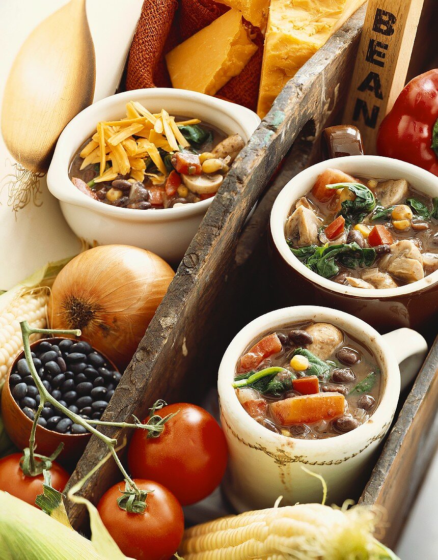 Three Mugs of Hearty Vegetable and Black Bean Soup with Fresh Soup Ingredients