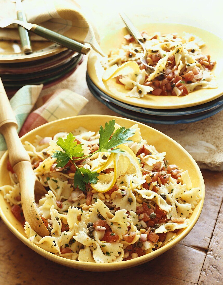 Farfalle Pasta Tossed with Fresh Tomatoes and Capers in Serving Bowl and Individual Bowl