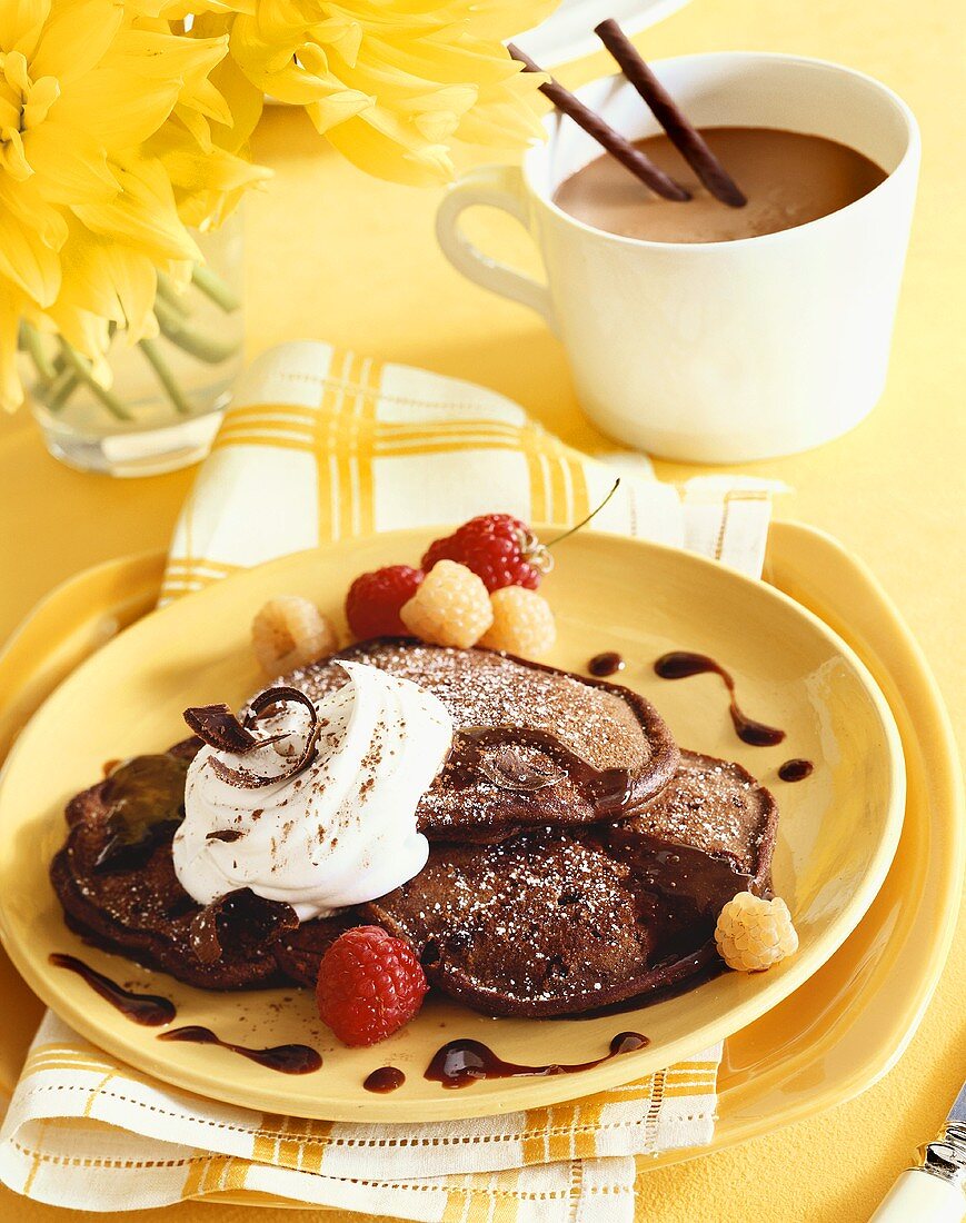 Chocolate Pancakes on a Plate with Whipped Cream and Red and Golden Raspberries