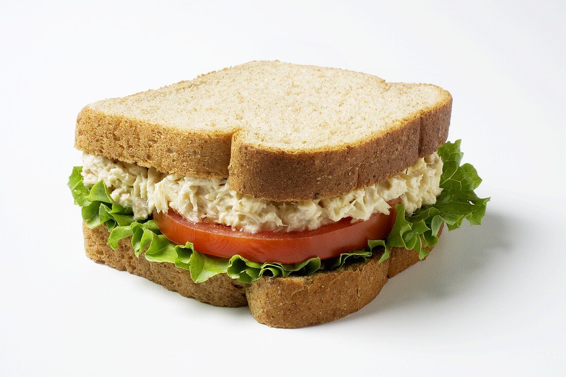 A Tuna salad sandwich with lettuce and tomato on whole wheat bread