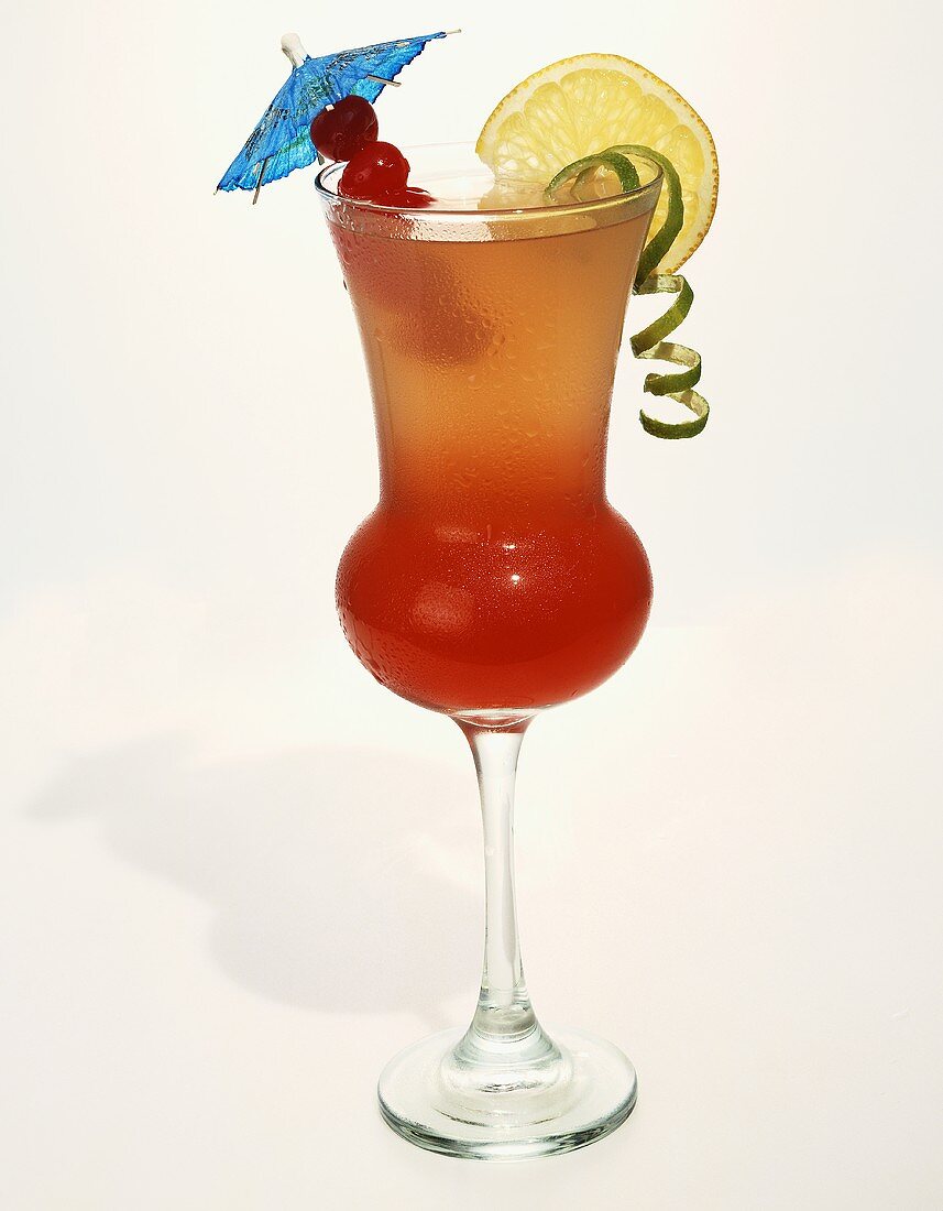 Mixed Drink in a Wet Glass with Cocktail Umbrella and Fruit Garnish; White Background