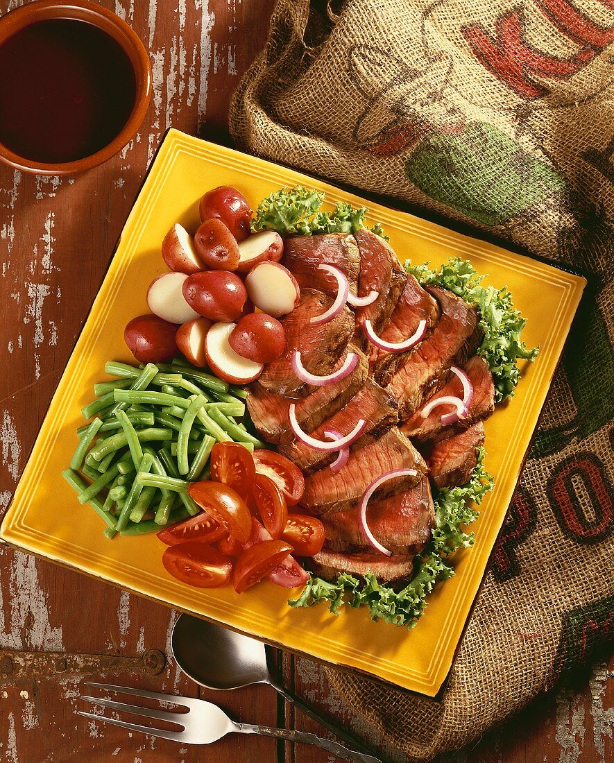 Steak Salad; Sliced Steak Over Lettuce with Tomatoes, Green Beans, Red Potatoes and Onion Slices