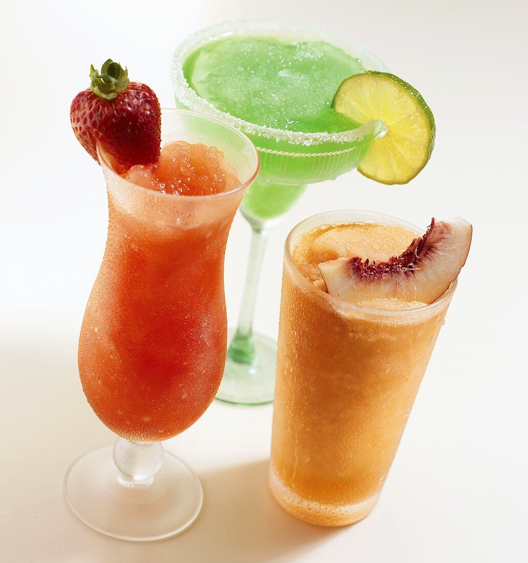 Three frozen cocktails garnished with fruit