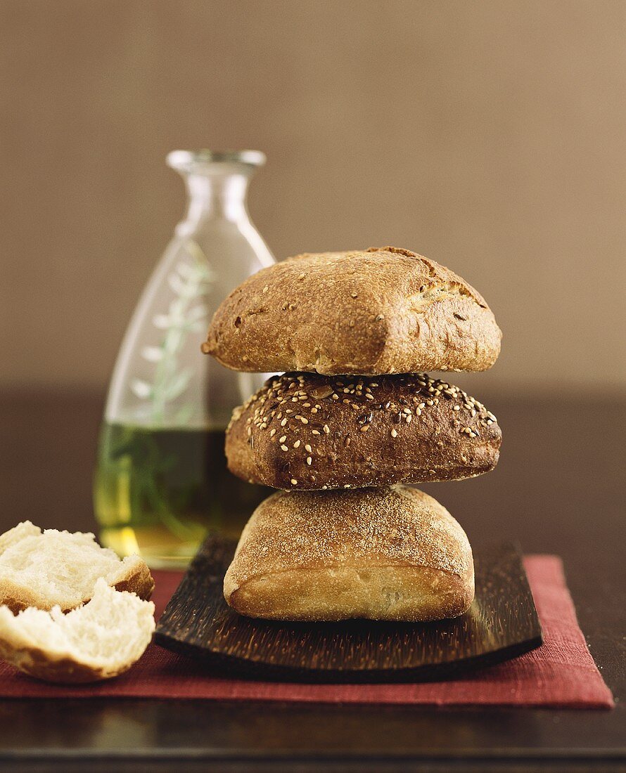 Drei Brote, gestapelt, vor Flasche Olivenöl