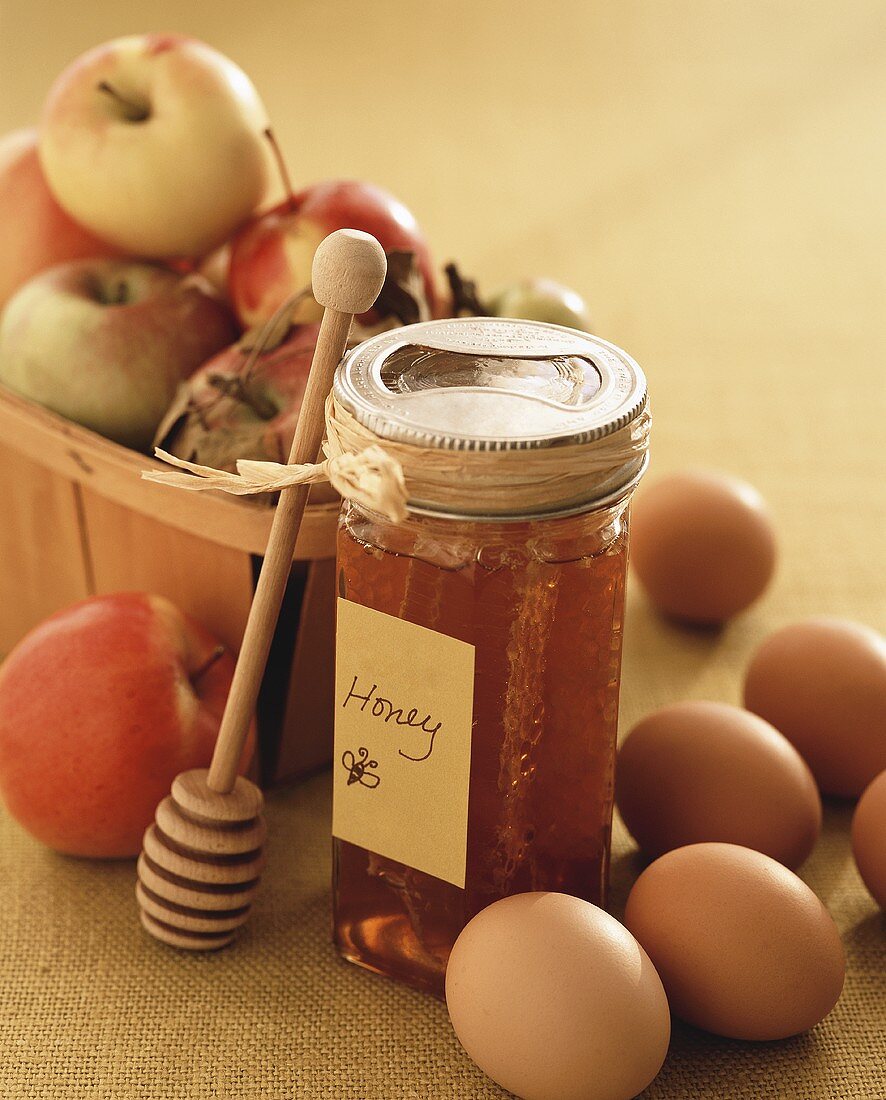 Honig mit Honiglöffel, Eier und Äpfel