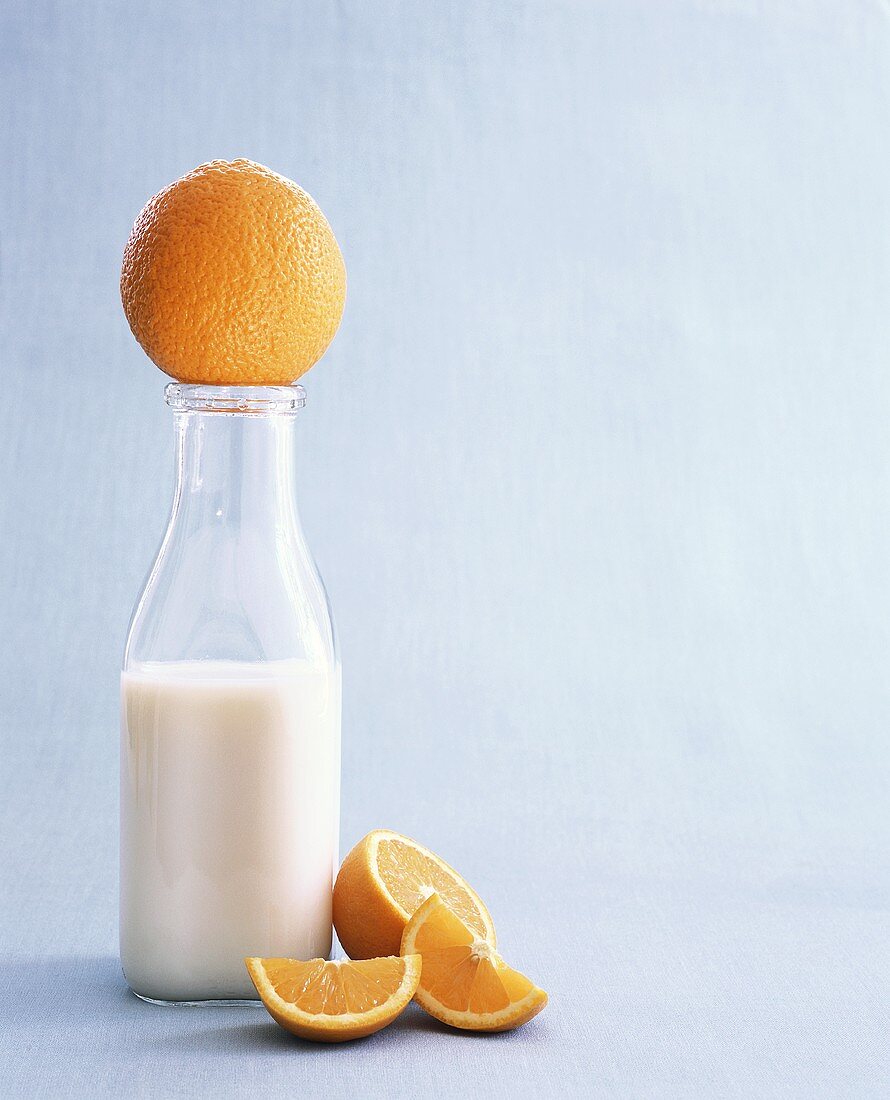 Flasche Milch mit ganzer Orange und Orangenschnitzen