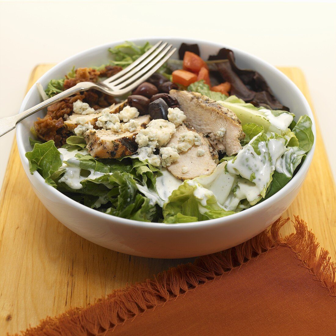 Bowl of Chicken, Olive, Bacon, Tomato and Blue Cheese Salad with a Fork