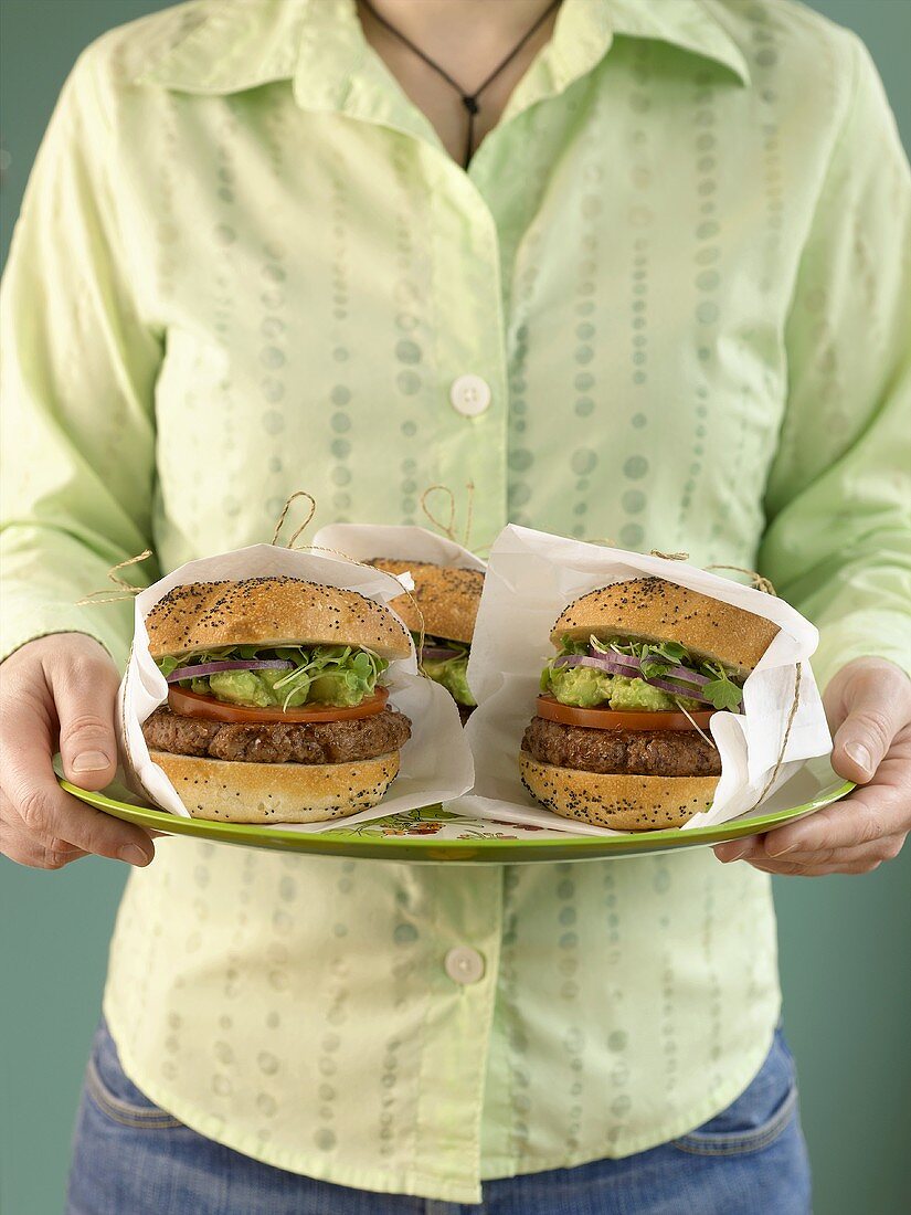 Woman carrying three hamburgers wrapped in napkins