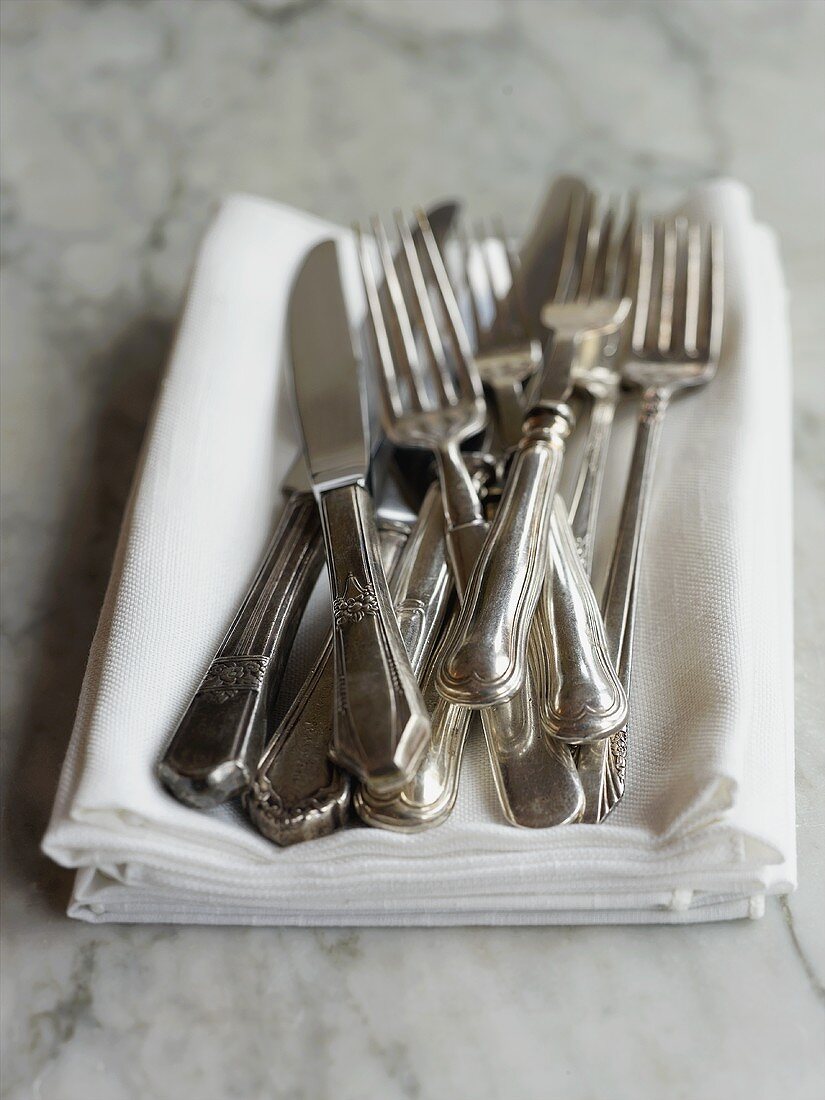 Forks and Knives Piled on a Pile of White Cloth Napkins