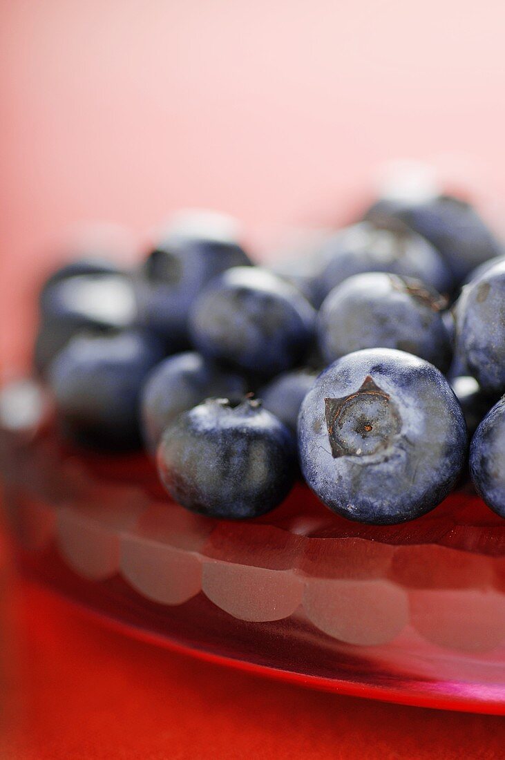 Heidelbeeren auf rotem Glasteller (Close Up)