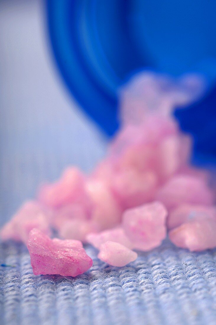 Pink Bath Salts Spilling From a Blue Bottle