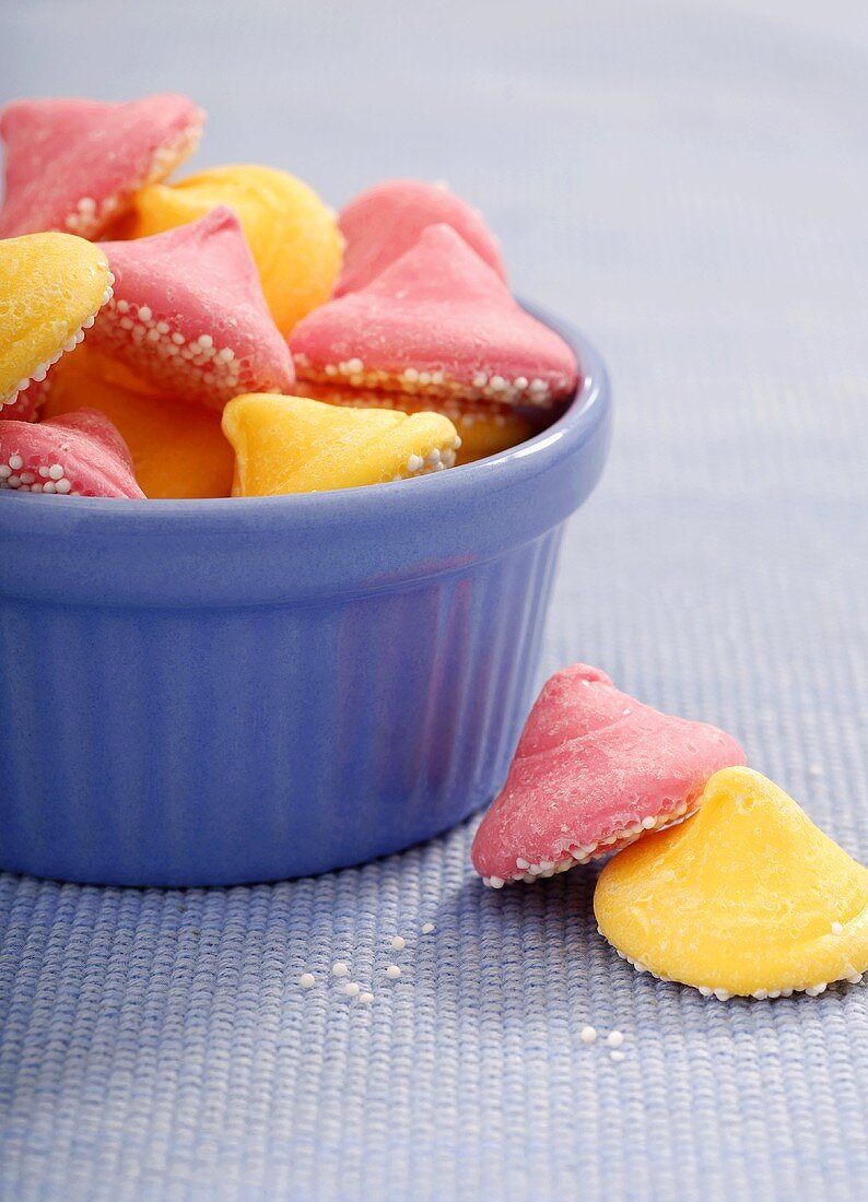Pink and Yellow Melty Mints In and Beside a Blue Glass Bowl