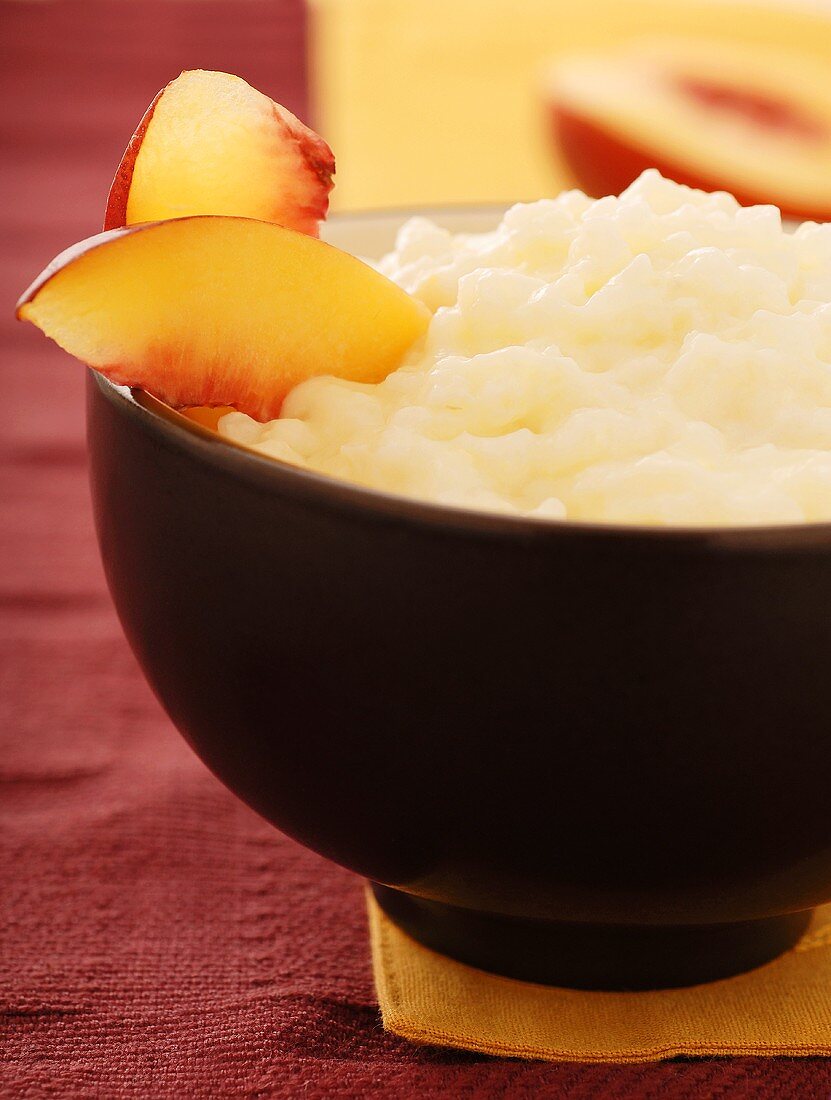 Rice Pudding Garnished with Peach Slices Served in a Black Bowl